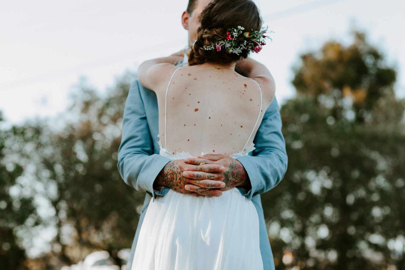 A tattooed groom holds his new bride at sunset